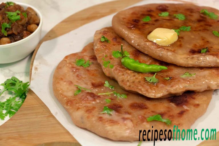 aloo paratha place on wooden food plater topping with butter and gren chili