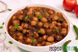 punjabi chole recipe serve on white bowl garnish with fresh coriander leaves